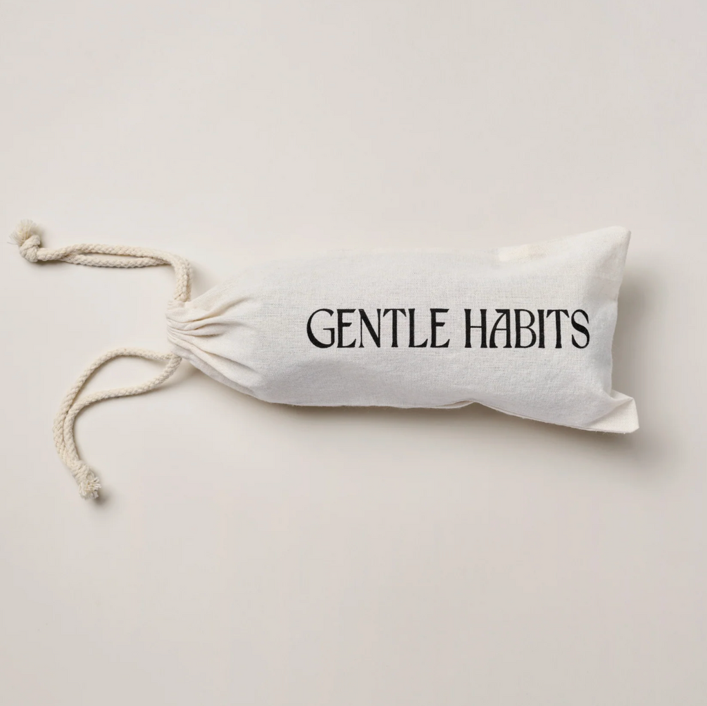 White drawstring bag with 'Gentle Habits' text on a light gray background