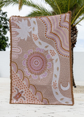 Decorative blanket with a intricate pattern on a wooden surface with palm trees in the background