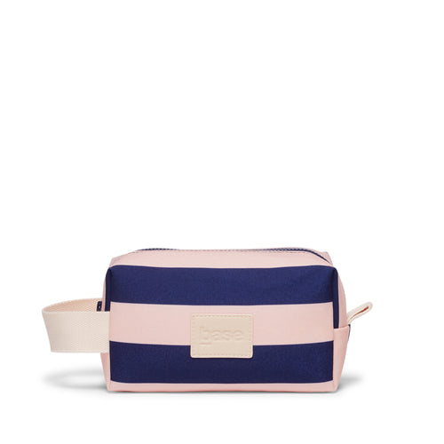 Navy and pink striped toiletry bag with beige tag on a white background
