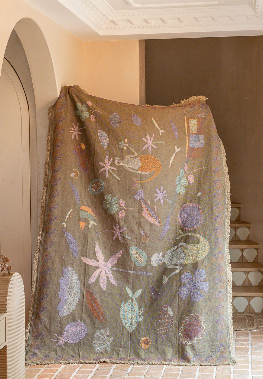 Decorative shawl with floral patterns draped over a chair in a room.