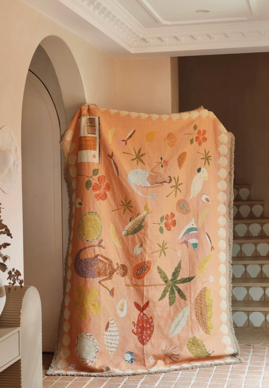 Decorative blanket with nature-themed patterns draped over a chair in a room.