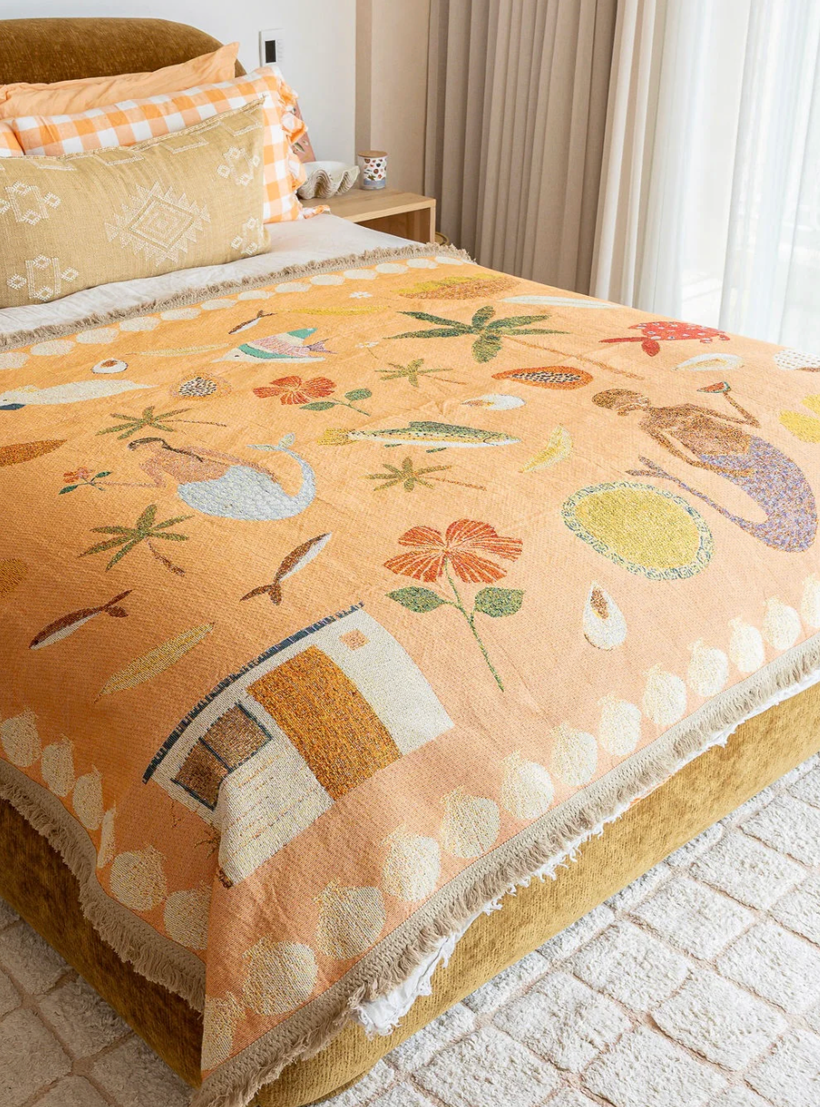 Decorative blanket with nature-themed patterns on a bed in a bedroom.