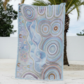 Decorative quilt with circular patterns on a wooden floor with palm trees in the background