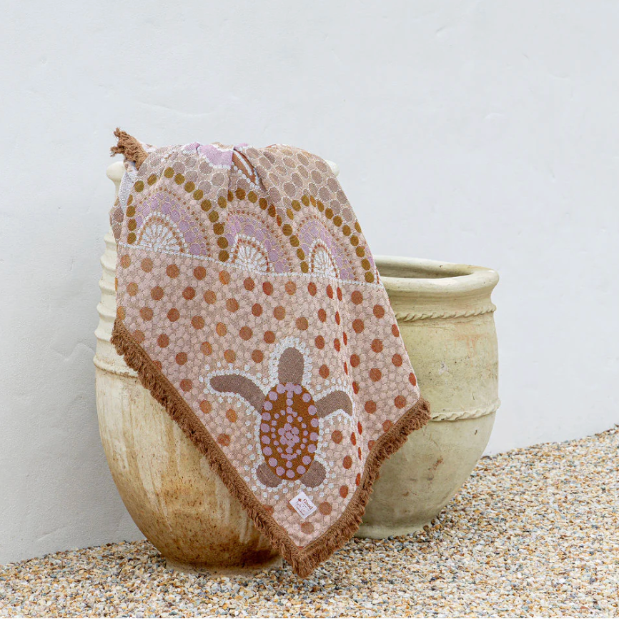 Textile with a turtle design draped over a textured surface against a white background