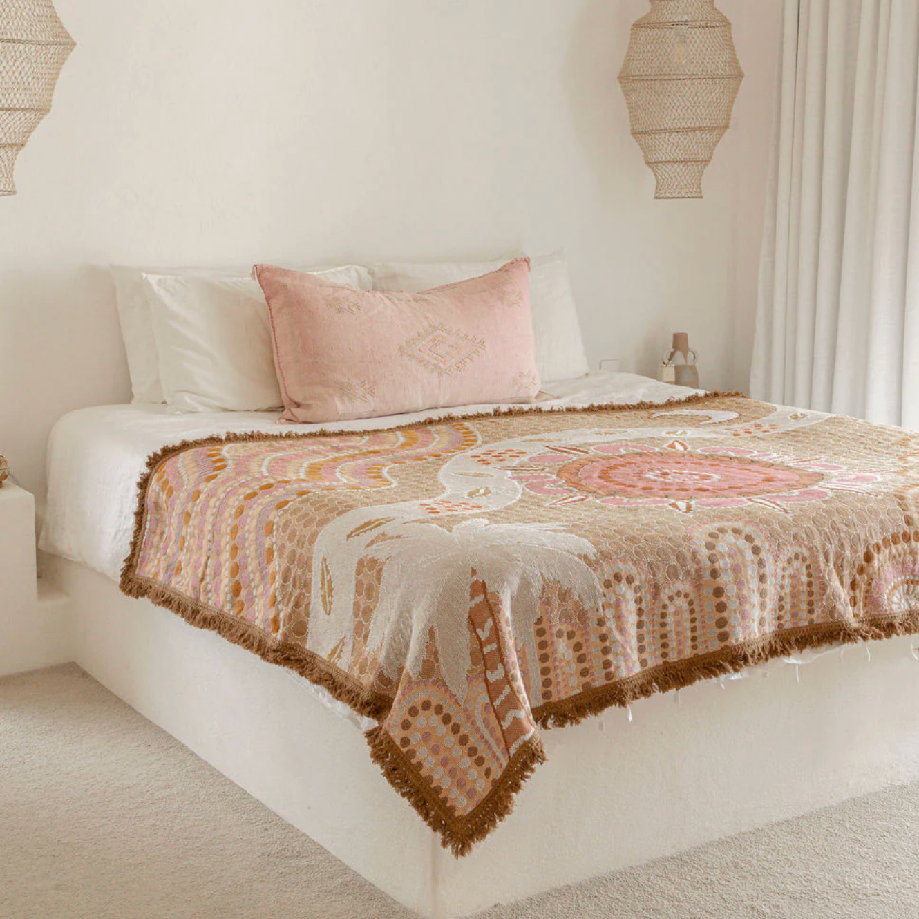 Bed with a patterned quilt and pink pillow in a bedroom setting