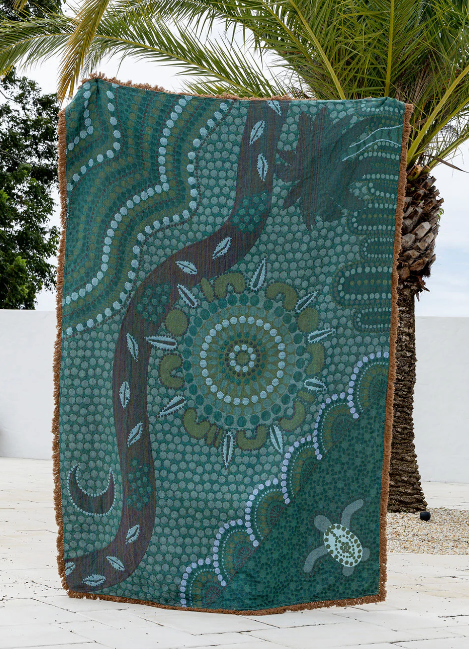 Decorative blanket with a nature-themed design featuring a snake and mandala pattern, placed outdoors.