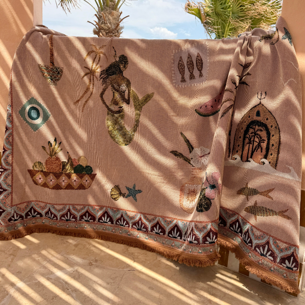 Decorative blanket with tribal patterns on a chair outdoors with palm trees in the background