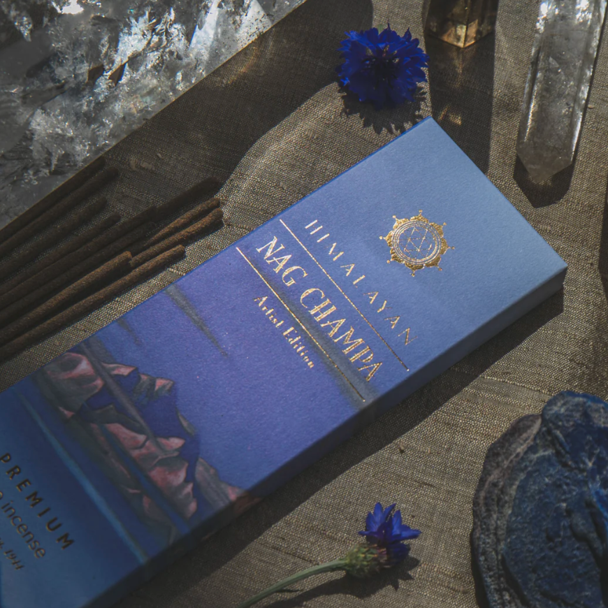 Blue box labeled 'Himalayan Nag Champa' on a textured surface with flowers.